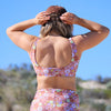 Person wearing a colorful floral sports bra and shorts with a clear blue sky background