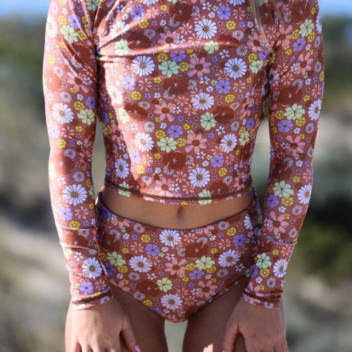 Floral patterned two-piece swimsuit with long sleeves on a blurred natural background