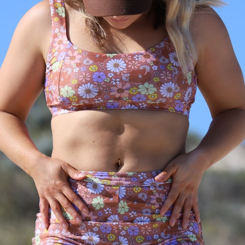 Woman wearing a colorful floral bikini set against a clear blue sky.