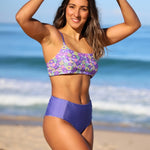 Woman wearing a purple bikini with floral top on a beach