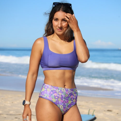 Woman in a purple bikini with floral pattern on a beach