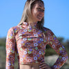 Woman wearing a floral long-sleeve top against a blue sky.