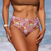 Person wearing a floral bikini with a blurred beach background