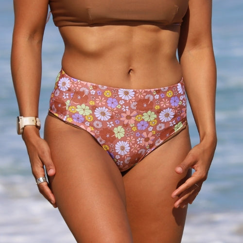 Person wearing a floral bikini with a blurred beach background