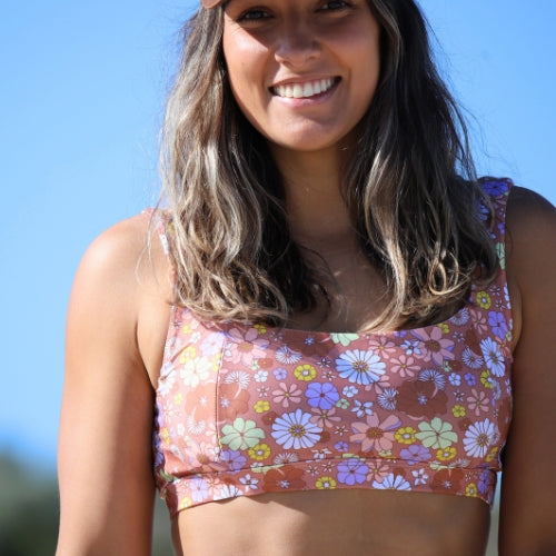 Woman wearing a floral-patterned tank top against a clear blue sky.