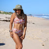 Woman in a floral bikini and hat on a beach