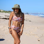Woman in a floral bikini and hat on a beach