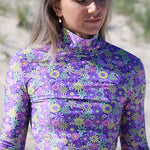 Person wearing a long-sleeve shirt with a colorful floral pattern outdoors.