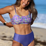 Woman wearing a purple floral bikini on a beach