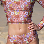 Person wearing a floral bikini set on a beach.