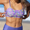 Person wearing a purple floral bikini on a beach