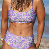 Woman wearing a colorful floral bikini set on a beach.